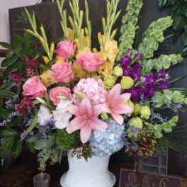 Mixed floral arrangement in a white vase with pink roses and lilies