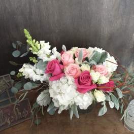 Pink and white rose arrangement with eucalyptus in a low container