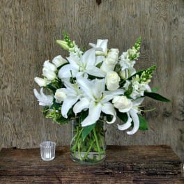 White lilies and roses arranged in a clear glass vase
