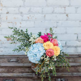 Bouquet of pastel roses and blue hydrangea in a glass vase