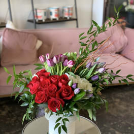 Bouquet of red roses and purple tulips in a white vase