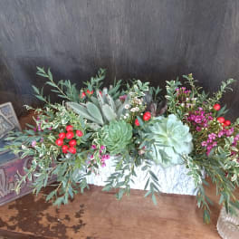Succulent arrangement with red berries in a white container
