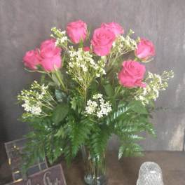 Pink roses in a glass vase with white filler flowers