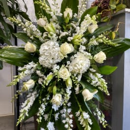 Large white floral standing spray with lilies, roses, and hydrangeas