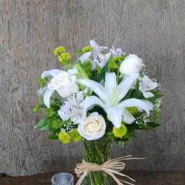White lilies and roses in a glass vase with green accents