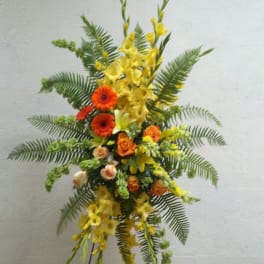 Tall floral spray with yellow and orange flowers on a stand