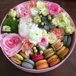 Round pink box with roses, carnations, and macarons