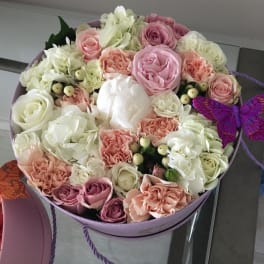 Round box of pink and white roses with carnations and a purple butterfly decoration