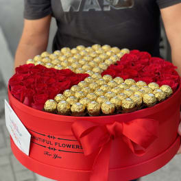 Heart-shaped box of red roses and gold-wrapped chocolates with a red bow