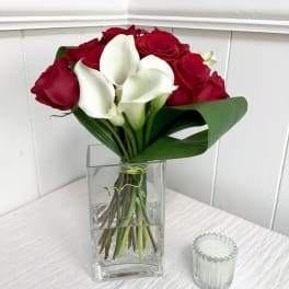 Red roses and white calla lilies in a clear glass vase