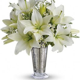 White lilies arranged in a tall silver vase