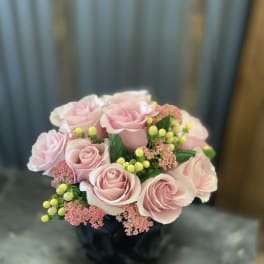 Pink rose bouquet with yellow berry accents in a dark vase