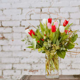 Bouquet of red, white, and pink tulips in a clear glass vase