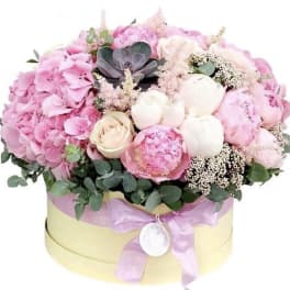 Pink and white floral arrangement in a round hat box with a ribbon