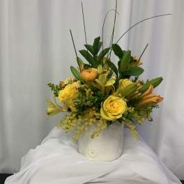 Yellow roses and lilies arranged in a white ceramic pot