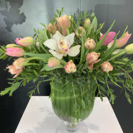 Pink tulips and a white orchid in a green glass vase