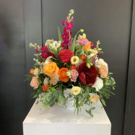 Colorful mixed flower arrangement in a white container