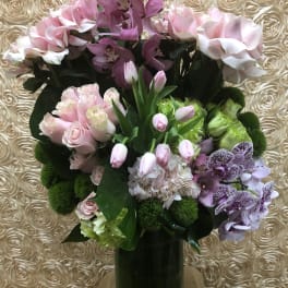 Pink and purple floral arrangement in a tall glass vase