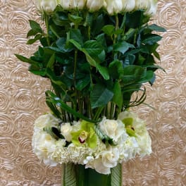 Tall white rose arrangement with orchids and hydrangeas in a glass vase