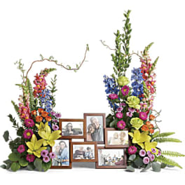 Floral memorial display with framed photos and colorful flowers