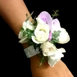 White rose wrist corsage with light lavender accents on a rhinestone band.