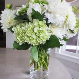 White flowers and pale green hydrangeas in a clear glass vase
