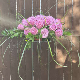 Pink roses arranged with long looping grass in a low stand