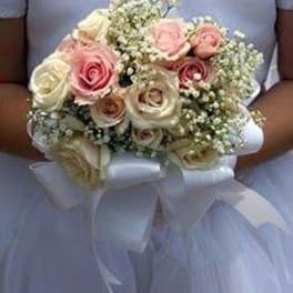 Bridal bouquet of pink and cream roses with baby's breath and white ribbon