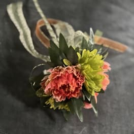 Small floral corsage with pink and yellow blooms on a ribbon band