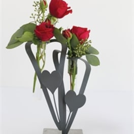 Two small red rose arrangements in a concrete holder