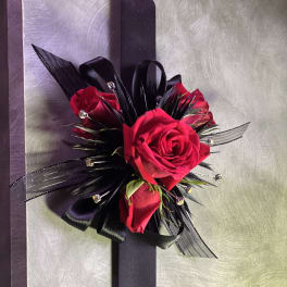 Red rose corsage with black ribbon on a silver background
