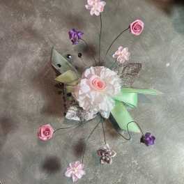 Small decorative floral corsage with pink and white flowers and ribbon