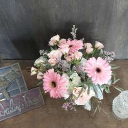 Pink gerbera daisies and pale roses arranged on a table