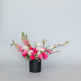Pink and white floral arrangement in a black cylindrical vase