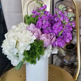 Purple and white flowers arranged in a white textured vase