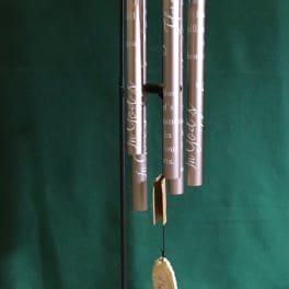 Hanging metal wind chime with engraved tubes and a decorative top