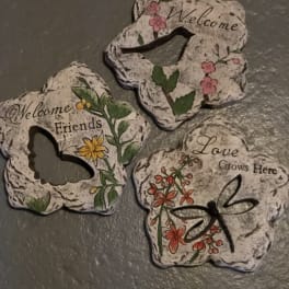 Three decorative stone plaques with floral designs and welcome messages