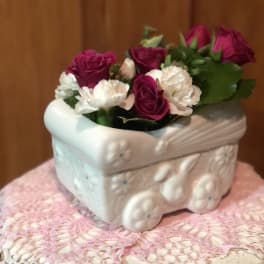 Pink and white roses arranged in a white ceramic planter