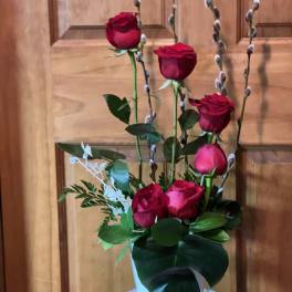 Tall arrangement of red roses with pussy willow stems in a white container