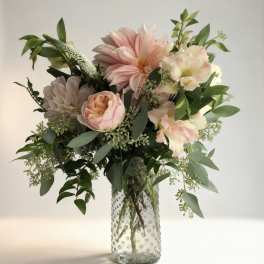 Pink and cream flowers in a clear textured glass vase