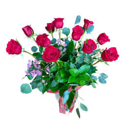 Arrangement of red roses with small pink blooms in a clear glass vase with a red ribbon