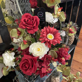 Arrangement of red roses, white blooms, and orchids in a decorative container