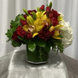 Red roses and yellow orchids in a glass vase with white hydrangea