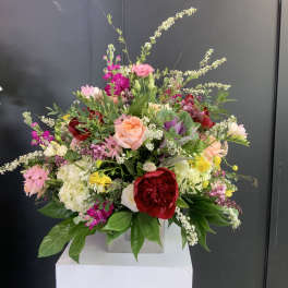 Large mixed bouquet with pink, red, white, and yellow flowers in a square vase