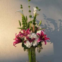 Tall bouquet of pink lilies and white calla lilies in a glass vase