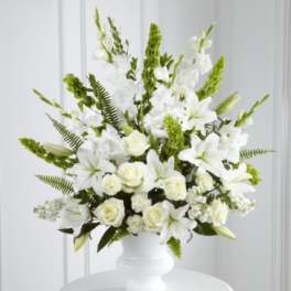 White floral arrangement in a white vase with green accents