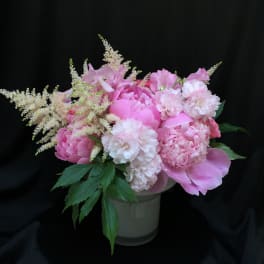 Pink floral arrangement in a white vase with feathery white accents
