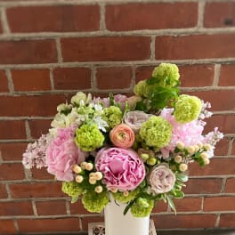 Pink and green floral arrangement in a white vase
