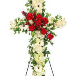 Standing floral cross with red roses and white flowers on an easel