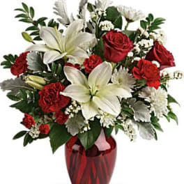 Red roses and white lilies arranged in a red glass vase